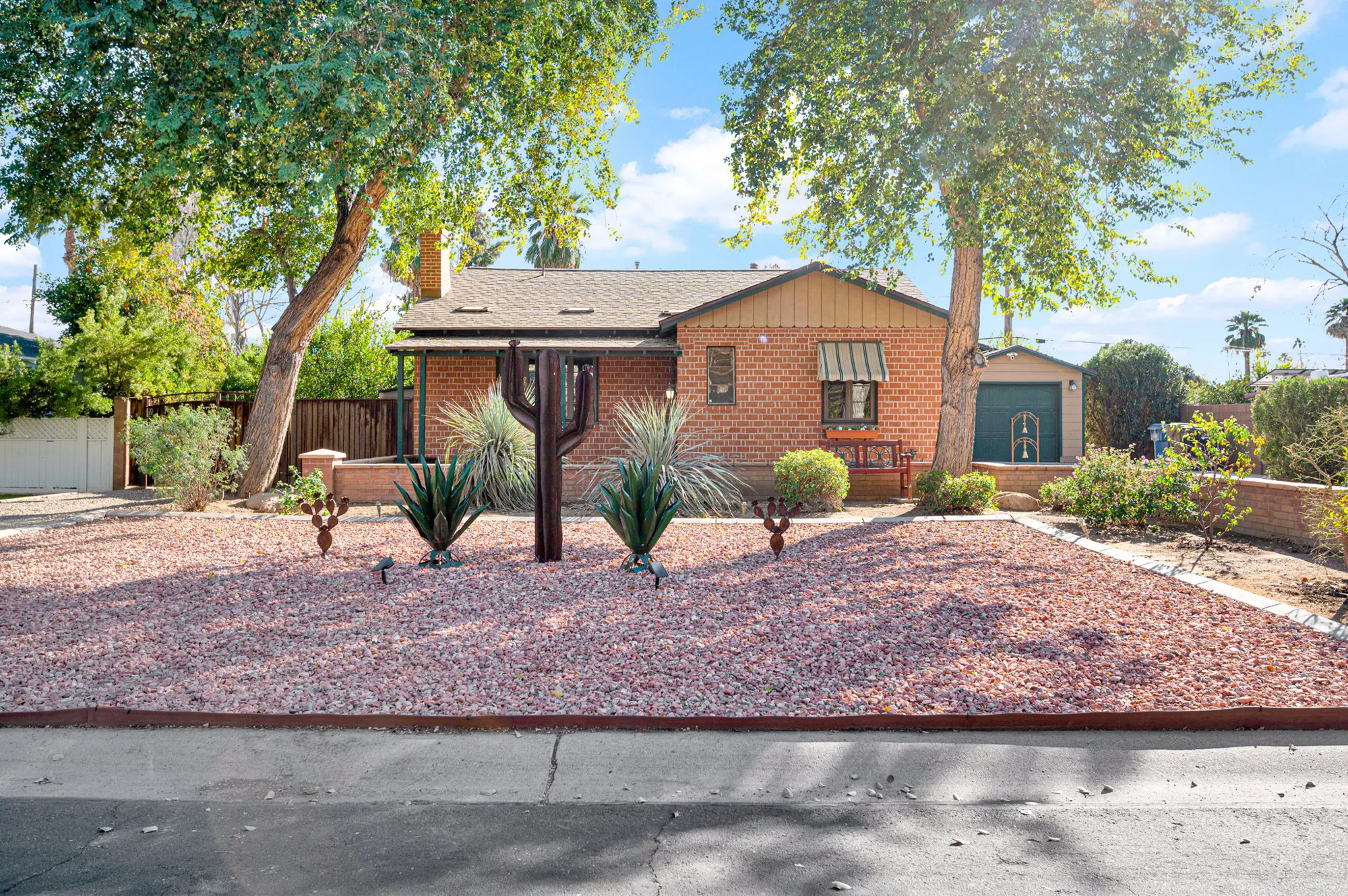 Brick custom home at 311 W Georgia Ave behind a desert-planted front yard and old shade trees.